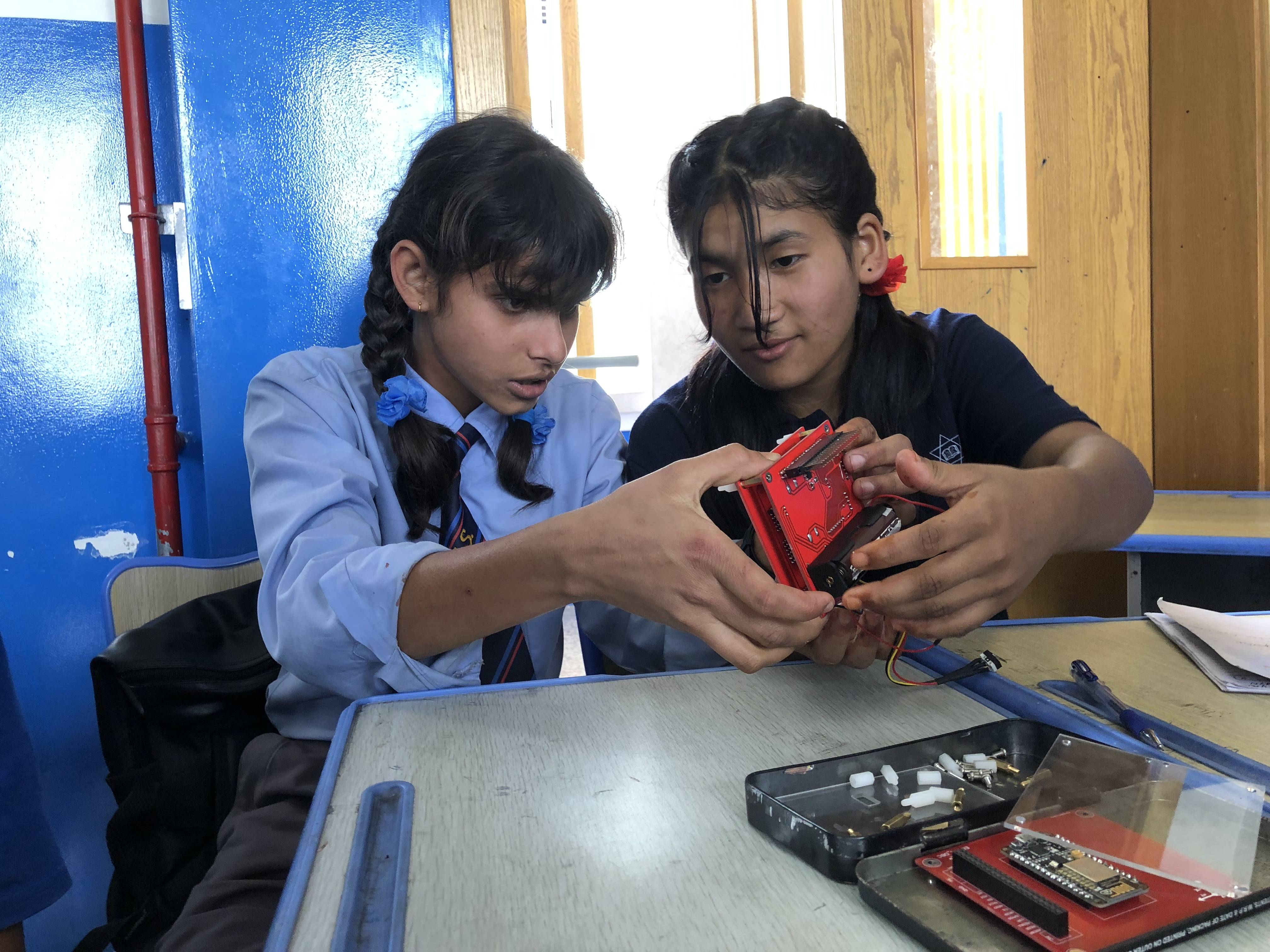 Girls observing satellite components